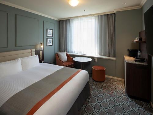 a hotel room with a bed and a table and a window at Sapporo Grand Hotel in Sapporo
