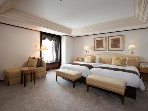 a large hotel room with two beds and a couch at Sapporo Grand Hotel in Sapporo