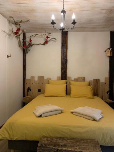 a bedroom with a large yellow bed with two pillows at Domaine des Combes - La Ferme aux Anes 14 pers. in Millau