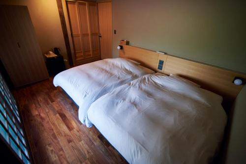 two beds in a hotel room with white sheets at Travel Stop UNNOWA in Tomi