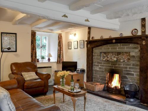 a living room with a fireplace and a couch and chair at Rowlandson Ground Cottage in High Yewdale