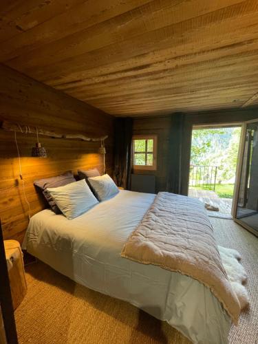 une chambre avec un grand lit avec un plafond en bois dans l'établissement Le Pika, à Hauteluce