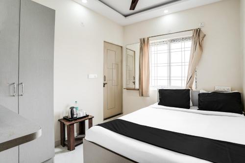 a white bedroom with a large bed and a window at Super Hotel O Bangalore Near Reva Circle Formerly CKA Boarding in Bengaluru