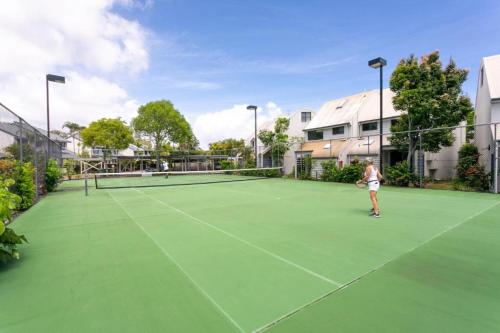 a woman playing tennis on a tennis court at Nautilus Noosa Resort in Noosaville