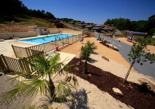 une piscine avec des palmiers dans un complexe hôtelier dans l'établissement Pomette 3p 4pers, à Cazals