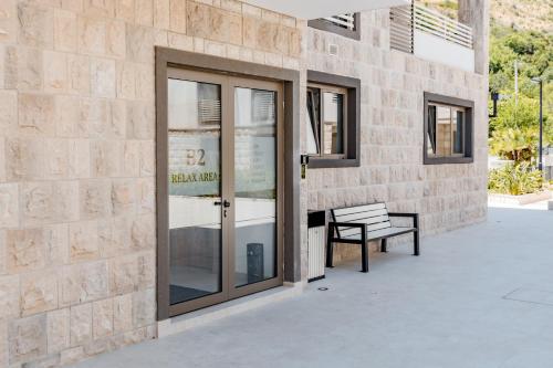 a building with a glass door and a bench at Hi Montenegro - RiverSide Apartment in Igalo