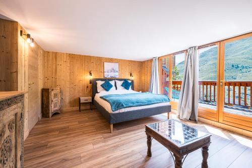 Les BruyèresにあるChalet Gabrielle Luxe ski aux piedsのベッドと大きな窓のある寝室