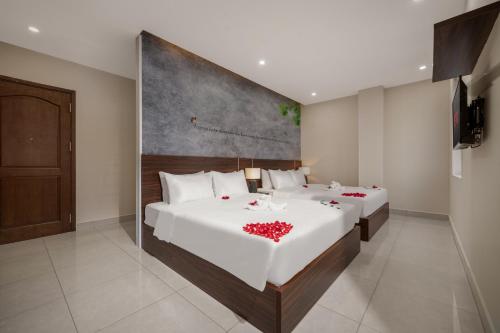 a bedroom with two beds with red flowers on them at KLY Hotel Vung Tau in Vung Tau