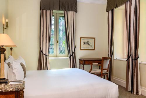 a bedroom with a bed and a desk and a window at Hotel de la Cité Carcassonne - MGallery Collection in Carcassonne