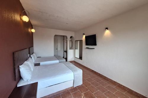 a hotel room with two beds and a flat screen tv at Capital O Hotel Rolovi Cancún in Cancún