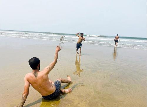 a group of men playing in the water on the beach at Rococo mandrem beach resort in Old Goa