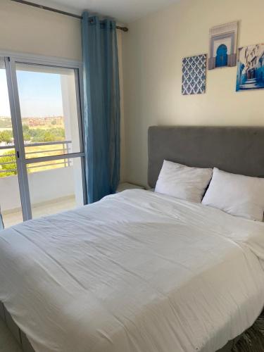 um quarto com uma grande cama branca e uma varanda em Meknès cosy près Médina em Meknès
