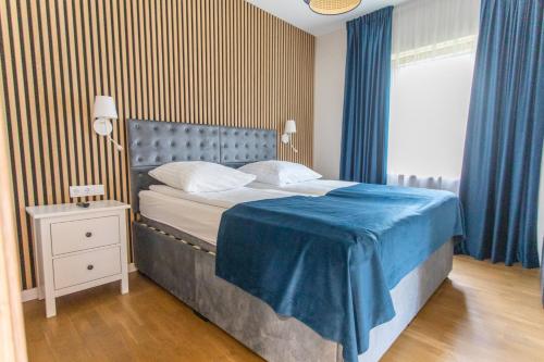 a bedroom with a bed with a blue blanket on it at Poilsio sodyba "Spalio krantas" in Giedraičiai
