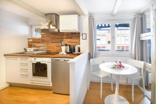 una pequeña cocina con mesa y estufa blanca en Cigogne Dorée - Strasbourg Centre Historique, en Estrasburgo