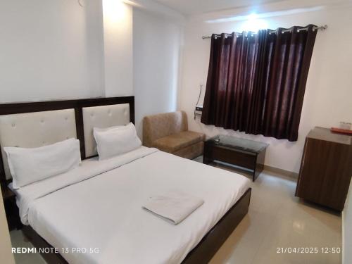 a bedroom with a large white bed and a chair at Hotel Navgrah Palace in Haridwār