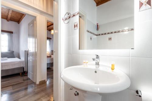 a white bathroom with a sink and a bedroom at Naxian Queen Luxury Villas & Suites in Agia Anna Naxos