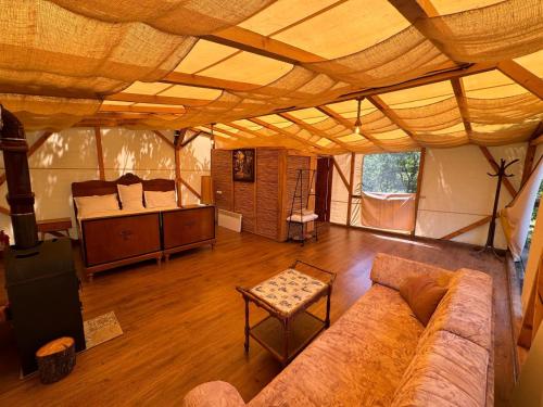 a living room with a couch in a large tent at Mesteceni Glamping in Nistoreşti