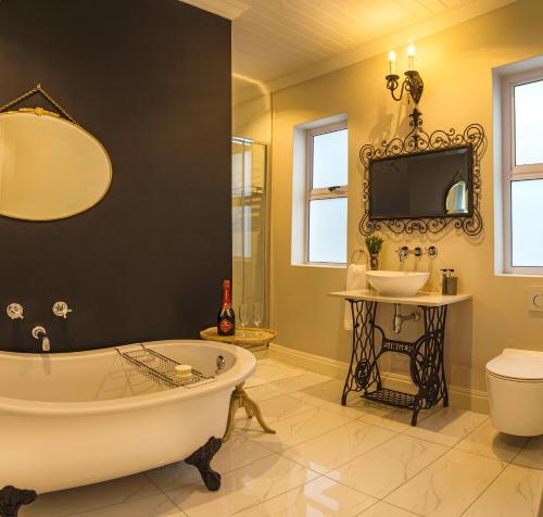 uma casa de banho com uma banheira, um lavatório e um WC. em Bright on 5th Guest house em Port Elizabeth