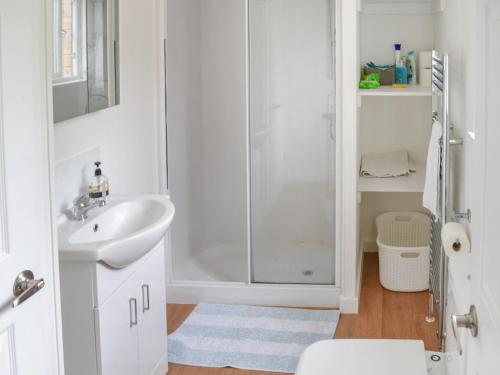 a white bathroom with a shower and a sink at Blackberry Lodge in Ripon