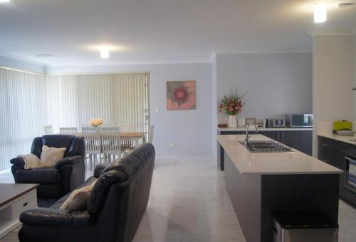 a kitchen and living room with two chairs and a couch at Spacious 4-Bedroom Baldivis Home - Sleeps 8 in Baldivis
