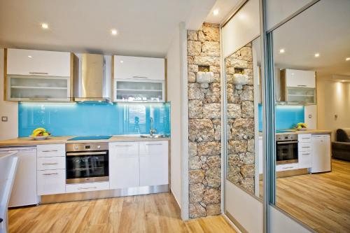 a kitchen with white cabinets and a stone wall at Paradise Stone Apartments in Bol