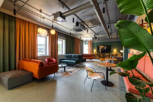 a living room with orange and green furniture and plants at DeSilva Inn Opole in Opole
