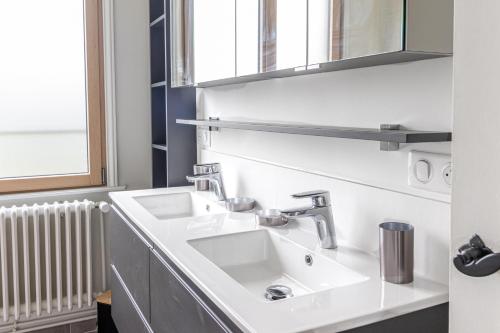 a bathroom with a white sink and a window at Le Logis - Charmante Maison Proche Plage in Rosendaël