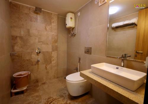 a bathroom with a white sink and a toilet at Lotus Hotel & Resort in Ambernath
