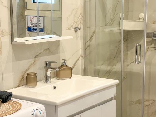 a white bathroom with a sink and a shower at Magda's Cosy House Fourka in Fourka