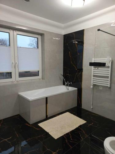a bathroom with a tub and a toilet and a window at Noclegi u Zosi 