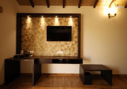 a room with a desk with a television on a wall at Lotus Hotel & Resort in Ambernath