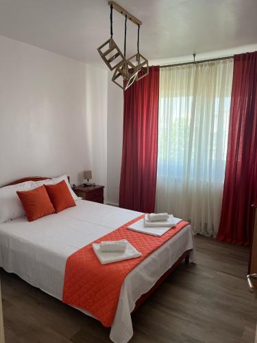 a bedroom with a large bed with red curtains at Dima Residence in Mangalia