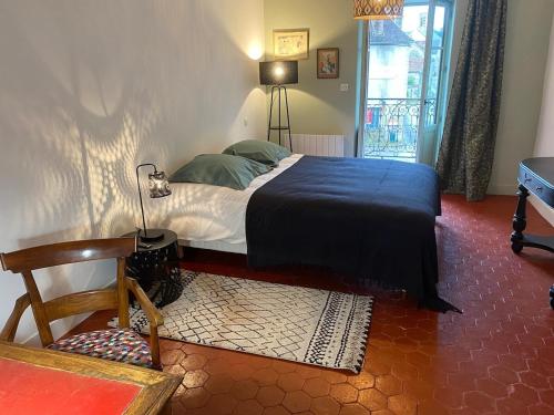 a bedroom with a bed and a chair and a window at Maison des Gardes in Noyers-sur-Serein in Noyers-sur-Serein