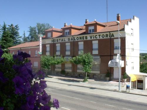 un edificio al lado de una calle con flores púrpuras en Hostal Salones Victoria, en Santa Marina del Rey