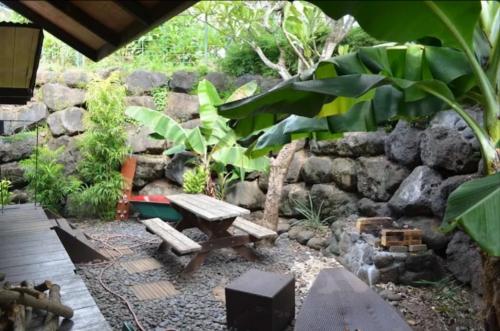a garden with a picnic table and a stone wall at Bungalow Temomea in Faaa