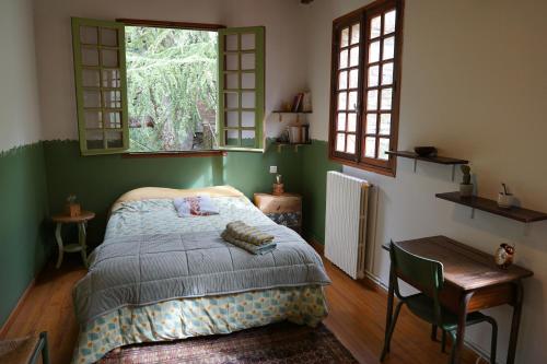 a bedroom with a bed and a table and windows at To a Book House in Corsica - chambres d'hôtes in Oletta
