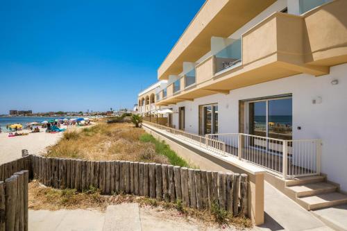 a house with a fence next to the beach at Nella Suites in Torre Lapillo