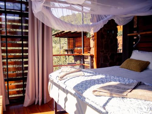 1 cama con dosel en una habitación con ventana en Sima Kade Bush Retreat, en Hekpoort