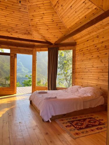 a bedroom with a bed in a wooden room with windows at Panoramic Wood Cabin in Itʼkhvisi