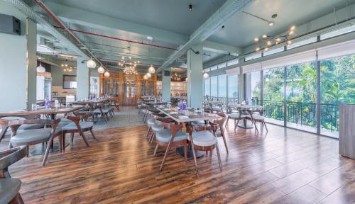 a restaurant with tables and chairs and large windows at Mystique Mayong Resort in Rāja Māyang