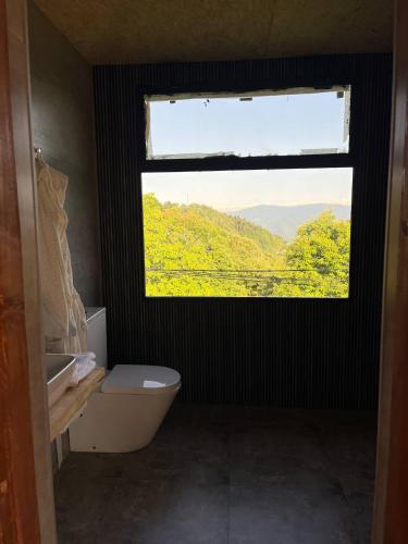 a bathroom with a window and a tub and a toilet at Panoramic Wood Cabin in Itʼkhvisi