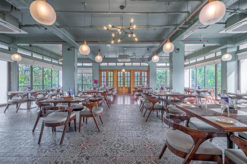 a dining room with tables and chairs and windows at Mystique Mayong Resort in Rāja Māyang
