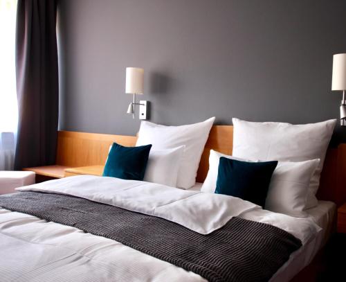 um quarto com uma cama grande com almofadas brancas e azuis em Hotel Tari em Würzburg