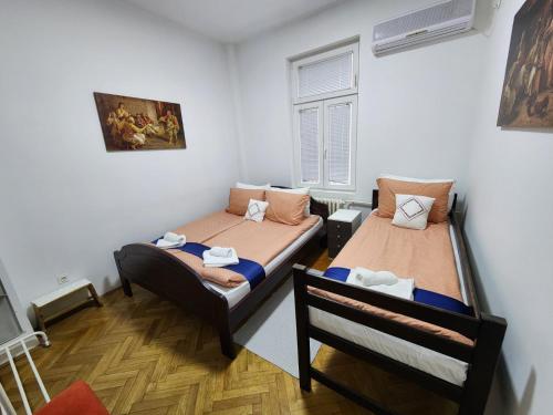 een kamer met twee bedden en een raam bij Authentic Belgrade Centre - New Year 2026 - 2 Apartments for large Groups in one building in Belgrado