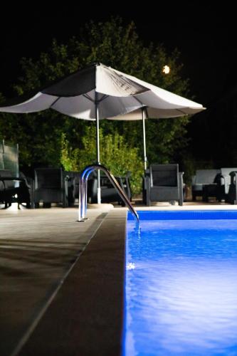 a white umbrella next to a swimming pool at night at Apartman Sedmica in Danilovgrad