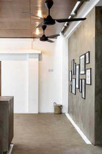 a ceiling fan in an empty room with art on the wall at SNUG Kuta in Kuta
