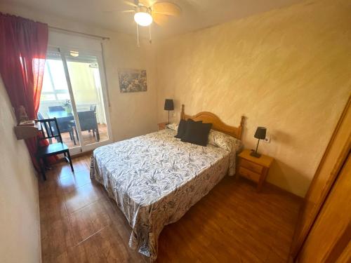 Un dormitorio con una cama y una puerta corrediza de vidrio. en Piso en 2ª linea de Playa TRJ2C, en La Venteta
