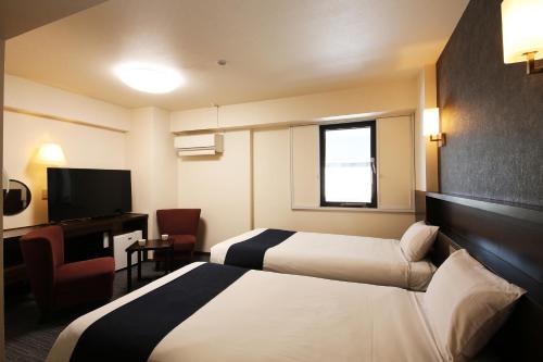 a hotel room with two beds and a television at Country Hotel Takayama in Takayama