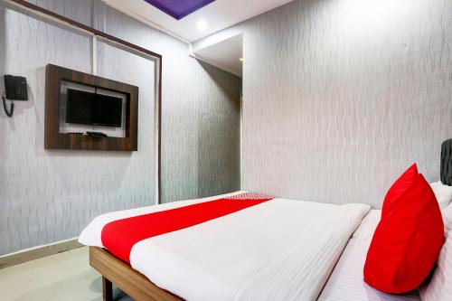 a bedroom with a bed with red pillows and a tv at Hotel O Yatri Yadgar in Mumbai