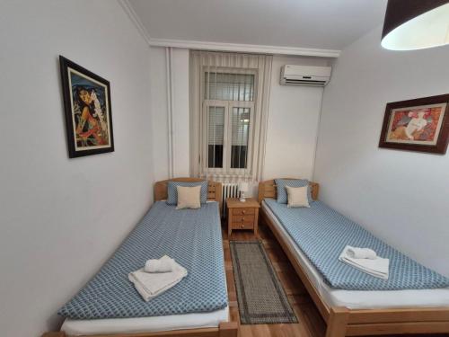 een kamer met twee bedden en een raam bij Authentic Belgrade Centre Apartment #5, Four bedrooms, One Full Bathroom, One Toilet in Belgrado
